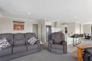 a living room with a couch and two chairs at Coast View Farm Stay in Opotiki