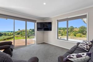 a living room with two couches and large windows at Coast View Farm Stay in Opotiki