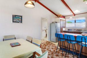 a kitchen with a table and chairs and a refrigerator at Amongst the Action - Te Kaha in Te Kaha