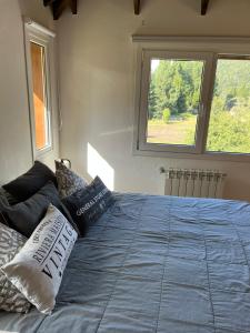 1 dormitorio con 1 cama azul y 2 almohadas en La Pampita en Villa Arelaquen Casa M14 en San Carlos de Bariloche