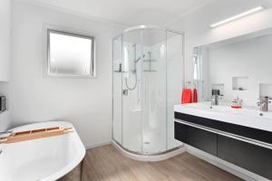 a bathroom with a shower and a tub and a sink at Waiotahe Executive Getaway in Opotiki