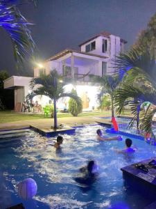 un grupo de personas en una piscina por la noche en cabaña Milan, en Aguachica