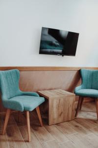 Duas cadeiras e uma mesa com uma televisão na parede em Vila Jelena em Jahorina