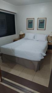 1 cama blanca grande en una habitación con 2 fotografías en FORTUNE RESIDENCE JARDINS - FLAT275 - Próximo da Avenida Paulista, en São Paulo