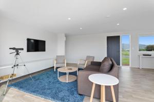 a living room with a couch and a tv and tables at Okioki Te Kaha Holiday Home in Te Kaha