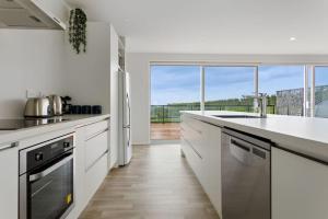 a kitchen with white appliances and a large window at Okioki Te Kaha Holiday Home in Te Kaha