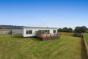 a small white house with a large yard at Okioki Te Kaha Holiday Home in Te Kaha