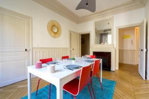 uma sala de jantar com uma mesa branca e cadeiras vermelhas em Charming apartment near Trocadero em Paris