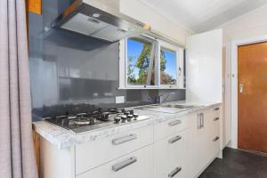 a kitchen with a stove and a sink and a window at Andam Cottage, Central Opotiki in Opotiki