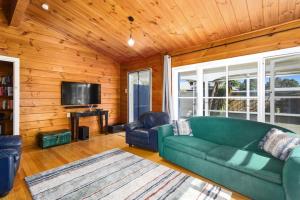 a living room with a green couch and a tv at Andam Cottage, Central Opotiki in Opotiki