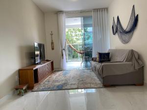 uma sala de estar com um sofá e uma porta de vidro deslizante em Apto de alto padrão 100 m da Praia de Costazul - WIFI 200MB - TV Smart - 2 Quartos - Garagem - Cozinha equipada - Churrasqueira em Rio das Ostras