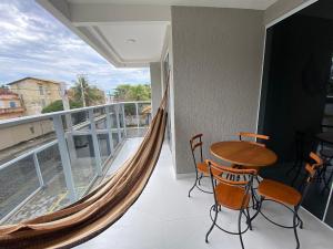 balcón con hamaca, mesa y sillas en Apto de alto padrão 100 m da Praia de Costazul - WIFI 200MB - TV Smart - 2 Quartos - Garagem - Cozinha equipada - Churrasqueira, en Rio das Ostras