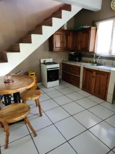 a kitchen with a table and a sink and a staircase at Aparta Hotel Palmerola in Comayagua