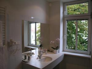 ein Badezimmer mit einem Waschbecken und einem Spiegel sowie zwei Fenstern in der Unterkunft Hotel Wiener Kindl in Wien