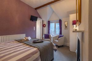 a bedroom with a bed and a chair and a window at Glyntwrog House in Betws-y-coed