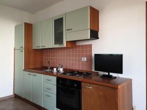 kuchnia z kuchenką i telewizorem na ladzie w obiekcie comfortable appartment close to the beach w mieście Isola Rossa