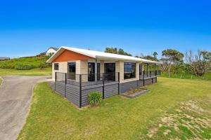 a house with an orange roof on a grass field at Kate and Harrys in Opotiki