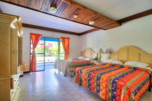 a hotel room with two beds and a balcony at Beach Break Resort in Jacó