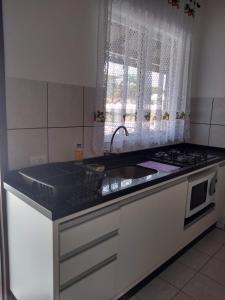 cocina con fregadero, fogones y ventana en Apartamentos Andréia, en Florianópolis