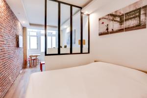 sypialnia z białym łóżkiem i ceglaną ścianą w obiekcie Modern apartment - 1BR-4P - Palais Garnier w Paryżu