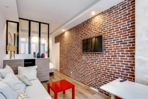 ceglana ściana w salonie z kanapą i telewizorem w obiekcie Modern apartment - 1BR-4P - Palais Garnier w Paryżu