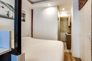 niewielka sypialnia z białym łóżkiem i kuchnią w obiekcie Modern apartment - 1BR-4P - Palais Garnier w Paryżu