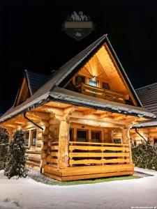 a log cabin in the snow at night at Janulkowe Domki in Zakopane
