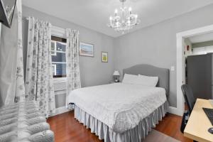 a white bedroom with a bed and a chandelier at Bright & Spacious 2Br apartment, mins from Downtown Boston, parking in Boston