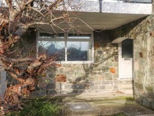 a stone house with a window and a door at 5 Ger Y Nant in Pwllheli