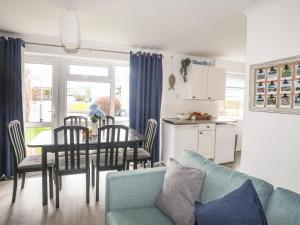 a living room with a blue couch and a table and chairs at 5 Ger Y Nant in Pwllheli