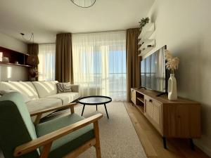 a living room with a couch and a tv at Klingerka brand new 1-bedroom apartment free parking in Nivy