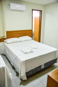 uma grande cama branca num quarto com um espelho em Pousada Tambaú Praia em João Pessoa