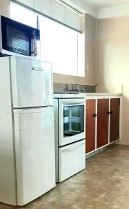 a kitchen with a white refrigerator and a sink at Aaron Court Motel in Timaru