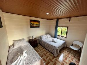 Habitación pequeña con 2 camas y ventana en Bonanza, en Monteverde