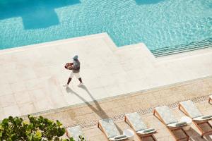 un uomo in piedi di fronte a una piscina di Four Seasons Resort Palm Beach a Palm Beach