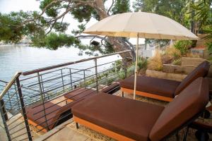 a patio with chairs and an umbrella next to the water at Splendid Hôtel & Spa in Bandol