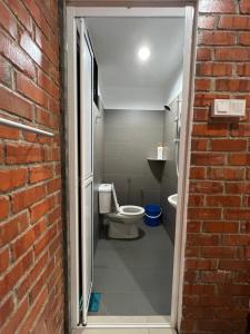 a bathroom with a toilet and a brick wall at Ujud Sepakat Homestay in Melaka