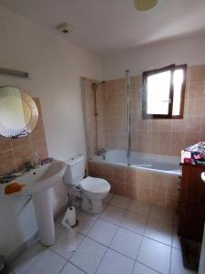 a bathroom with a toilet and a tub and a sink at Villa Lilas in Doumen