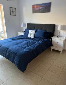 ein Bett mit blauer Decke in einem Schlafzimmer in der Unterkunft Mountain View Apartment - Polis in Polis Chrysochous