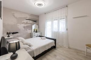 a white bedroom with a bed and a window at Mala Kate Apartments in Kaštela