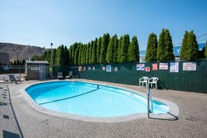 a large swimming pool with two chairs around it at Super 8 by Wyndham Kamloops East in Kamloops