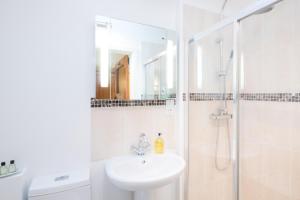a white bathroom with a sink and a shower at Pear Tree Cottages in Wedmore
