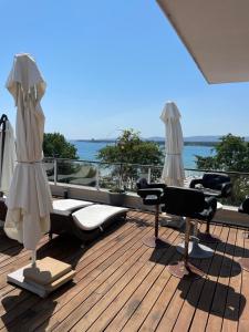 a deck with lounge chairs and umbrellas and the ocean at Deluxe Apartments Приморско in Primorsko