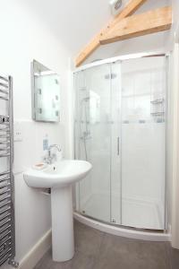 a white bathroom with a shower and a sink at Pear Tree Cottages in Wedmore