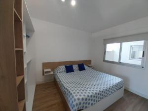 Un dormitorio con una cama con almohadas azules y una ventana en Apart Cid Campeador en Buenos Aires