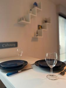 - une table avec deux assiettes et des verres à vin dans l'établissement Charmant Studio Front de Mer, à Cabourg