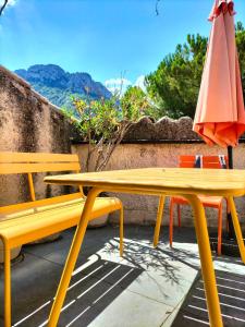 a yellow table and an umbrella and a table and chairs at Maison de ville 10 p. centre Buis les Baronnies in Buis-les-Baronnies