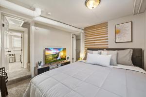 een slaapkamer met een groot wit bed en een televisie bij Peaceful Home w/ 4BR, Big Yard and amazing art in Denver