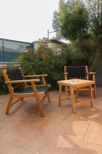 2 bancos de madera y una mesa en el patio en O&O Group- Huge & Lovely Unit 2BR 2BT By the beach en Rishon LeẔiyyon