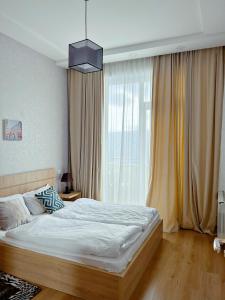 a bedroom with a bed and a large window at Vazi Aparthotel in Tbilisi City